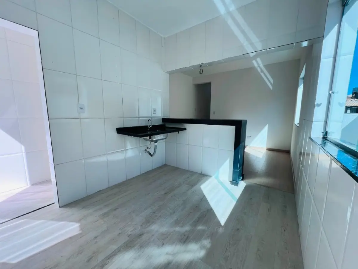 Cozinha americana com bancada em granito preto, piso vinílico e iluminação natural