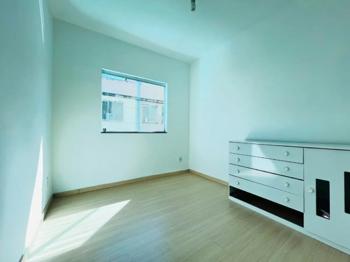 Quarto amplo com piso laminado claro e janela grande