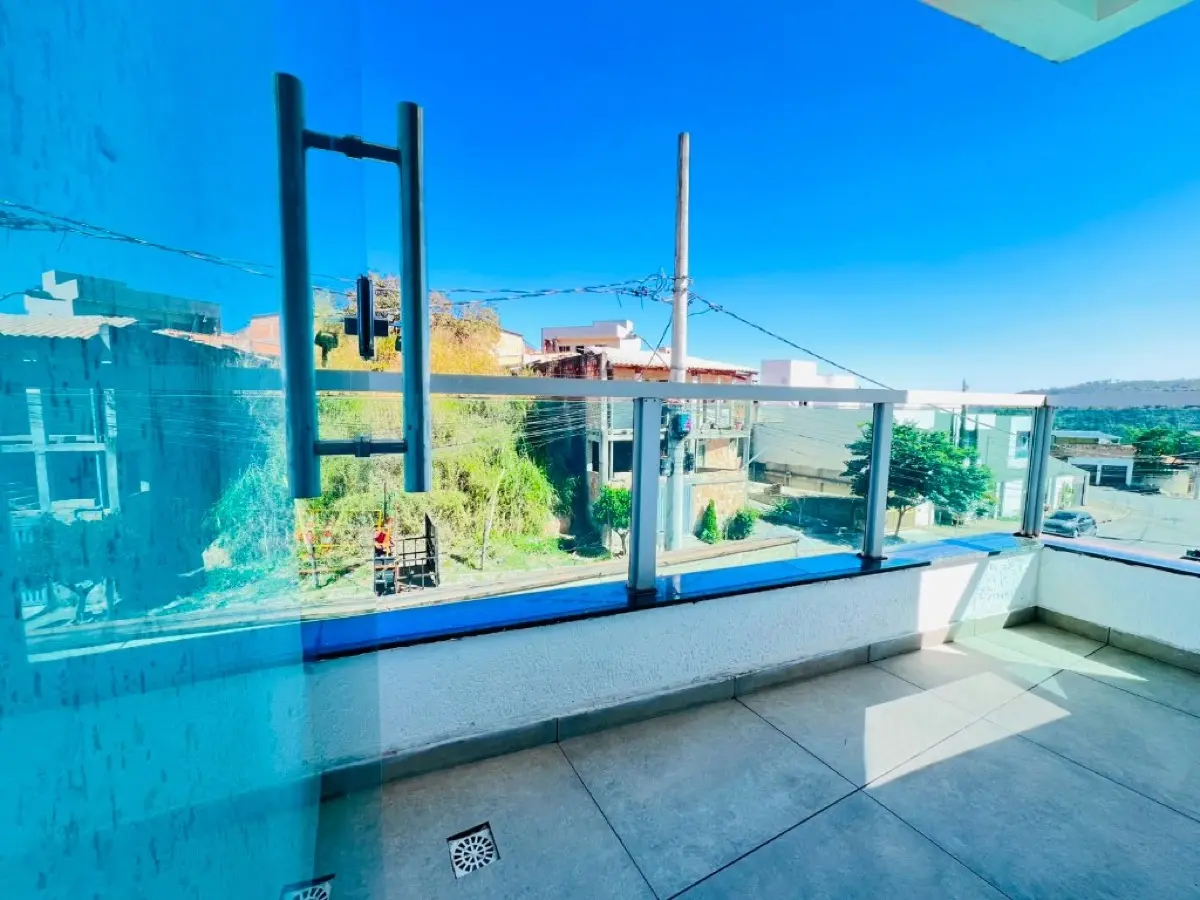 Sacada da suíte com guarda-corpo de vidro e vista do bairro em Sarzedo
